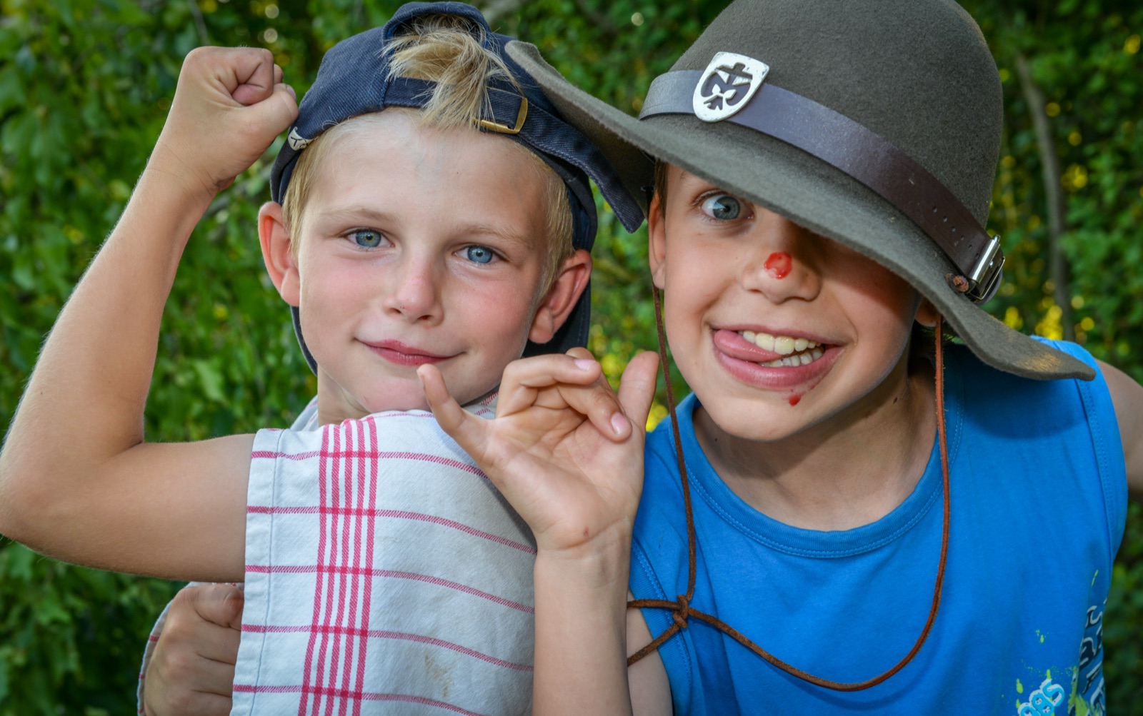 Zwei Kinder mit Hut lachen in die Kamera
